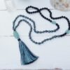 Close-up of a handmade mala beads necklace with a tassel on a white background, ideal for meditation.