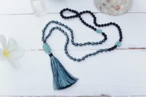 Close-up of a handmade mala beads necklace with a tassel on a white background, ideal for meditation.