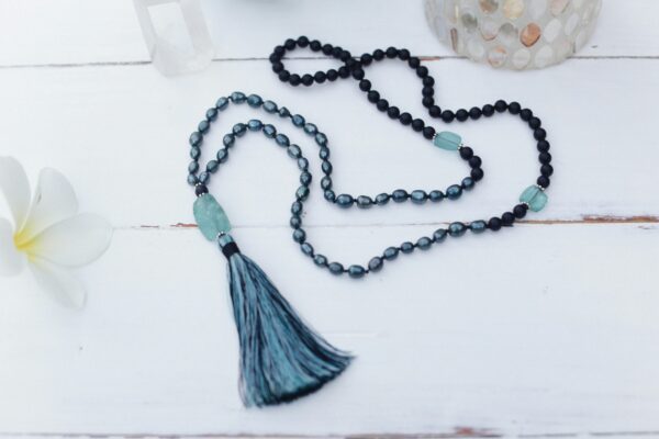 Close-up of a handmade mala beads necklace with a tassel on a white background, ideal for meditation.