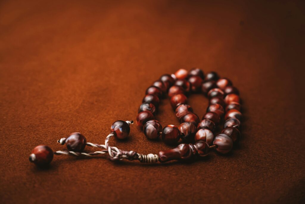A detailed shot of dark wood prayer beads resting on a soft brown fabric.