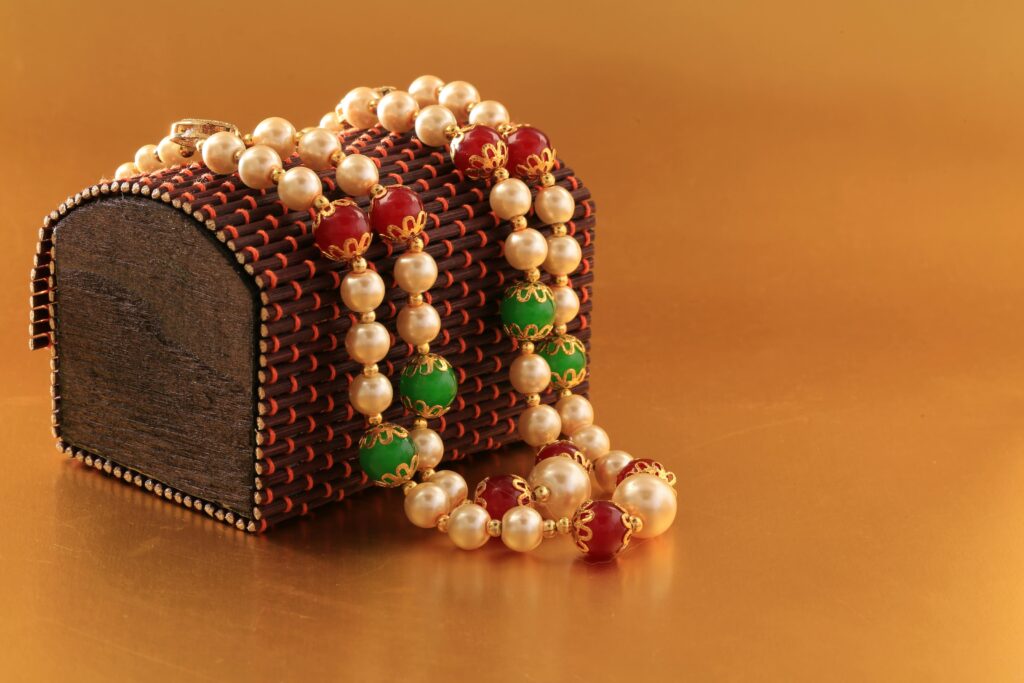 Close-up of a pearl necklace draped over an ornate wooden box, ideal for gifting.
