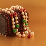 Close-up of a pearl necklace draped over an ornate wooden box, ideal for gifting.