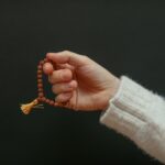 A close-up of a hand holding a beaded bracelet against a dark background.