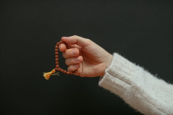 pexels photo 6634322 6634322 1 A close-up of a hand holding a beaded bracelet against a dark background.